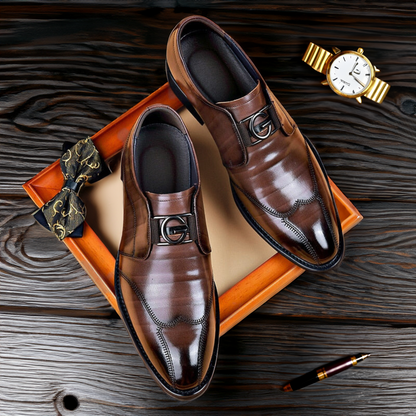 Brown wingtip bit loafers on a dark wood surface